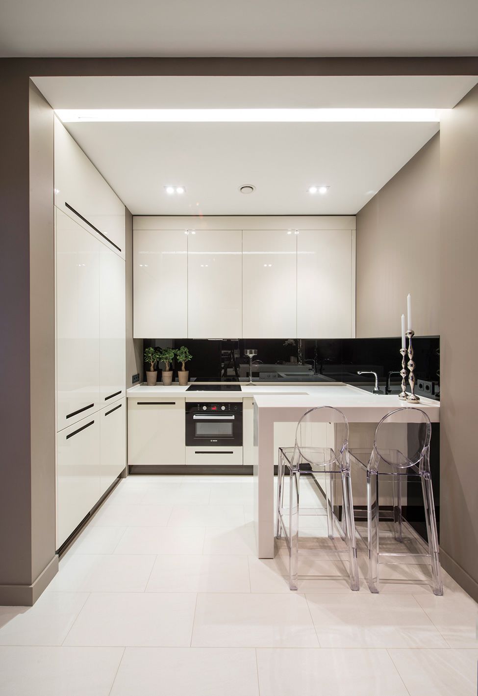 دکوراسیون آشپزخانه کوچک و مدرن با کابینت های سفید که به جای آویز، در آن چراغ سقفی توکار به کار رفته است